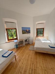 a bedroom with two beds and a desk and two windows at Ravelin Border Apartments in Narva
