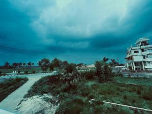 a dirt road in a field with a building at Hotel Aman Residency & Restaurant in Nalanda