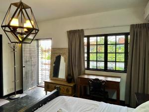 una camera da letto con un letto, una scrivania e finestre di Cozy Homestay King Bed withBalcony in Shared Bungalow SS2 PJ a Petaling Jaya