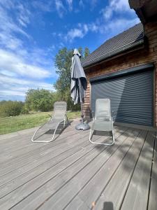 two chairs and an umbrella on a deck at Chalet de Russac - 6 personnes - Jardin clôturé avec terrasse aménagée in Turenne