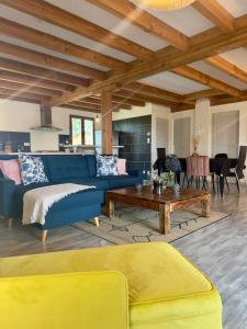 a living room with a blue couch and a table at Chalet de Russac - 6 personnes - Jardin clôturé avec terrasse aménagée in Turenne