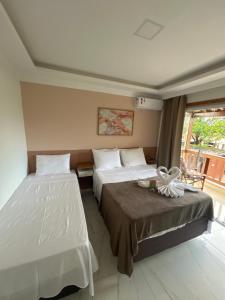 a hotel room with two beds and a balcony at Residencial Angelina in Praia do Forte