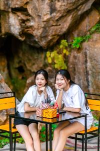 Dos niñas sentadas en una mesa con una canasta de comida en Song Toan Hotel, en Phong Nha