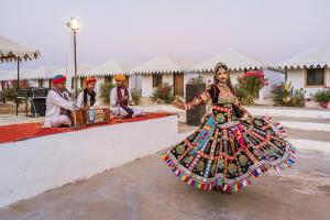 a woman in a colorful dress standing next to a group of people at Ozaki Desert Camp & Resort in Jaisalmer