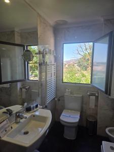 a bathroom with a sink and a toilet and a window at Hotel Leonor Mirón in Soria