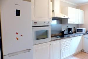 Spacious cocoon with nice garden close to the sea في ساناري سور مير: مطبخ فيه دواليب بيضاء وفرن ابيض