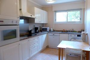 Spacious cocoon with nice garden close to the sea في ساناري سور مير: مطبخ مع دواليب بيضاء وطاولة