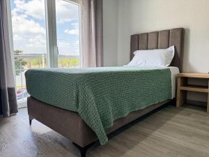 a bedroom with a bed with a green blanket on it at Flôr do Távora in Vila da Ponte