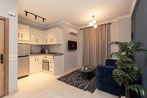 a living room with a blue couch and a kitchen at Travelholic Residence Near Mivida in Cairo