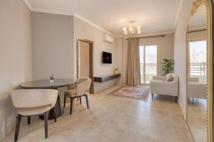 a living room with a table and chairs and a mirror at Travelholic Residence Near Mivida in Cairo
