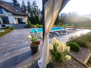 a view of a patio with flowers and a pool at Saskia Dwór & Spa willa z podgrzewanym basenem in Podmacharce