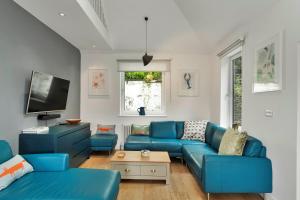 un soggiorno con divani blu e TV di Finest Retreats - Three Quarter Cottage a Fowey