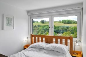 una camera da letto con un letto e una grande finestra di Finest Retreats - Three Quarter Cottage a Fowey