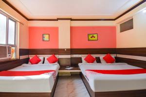 two beds in a room with red walls at Hotel Churu Palace in Jaipur