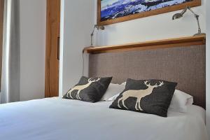 un letto con due cuscini e un cervo sopra di Tome, superbe appartement avec terrasse vue montagne a Champagny-en-Vanoise Altre 13 foto