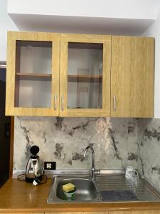 a kitchen counter with a sink and wooden cabinets at Mehmetaj’s Guest House in Durrës