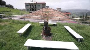 a group of benches in the grass with a building at Tulips Resorts - Village in Ooty +32 photos