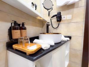a kitchen counter with a sink with a pot and bottles at Hôtel BANTU in Libreville +38 photos