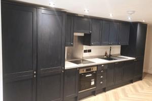 イーストボーンにあるCharming 1-Bed Retreat with Patio: Cozy & Centralの黒いキャビネットとシンクのあるキッチン