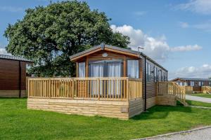 a wooden cabin with a large window in the grass at Clumber Park Lodges in Worksop