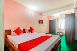 a bedroom with a large bed with red pillows at Hotel O Uzen Homestay in Lachung