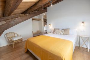 a bedroom with a large bed and a chair at Apartamentos Rurales Casa Carlota in Vegadeo