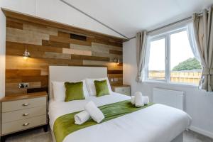 a bedroom with a white bed with a wooden accent wall at Clumber Park Lodges in Worksop