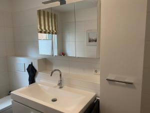 a white bathroom with a sink and a mirror at Exklusive Ferienwohnung im schönen Husum in Husum +13 photos