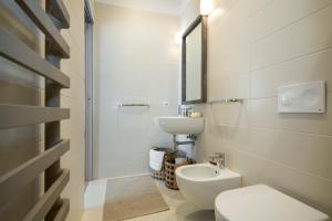 La salle de bains blanche est pourvue d'un lavabo et de toilettes. dans l'établissement Cavour 51, à Lecco
