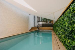 a swimming pool next to a brick wall and stairs at Hôtel Mademoiselle in Liège