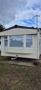 a small white trailer parked in a yard at Superb 8 Berth Dog Friendly Caravan To Hire In Norfolk Ref 10054B in Belton