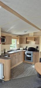 a large kitchen with wooden cabinets and a table at Superb 8 Berth Dog Friendly Caravan To Hire In Norfolk Ref 10054B in Belton