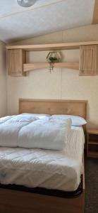 a bedroom with a bed with white sheets at Superb 8 Berth Dog Friendly Caravan To Hire In Norfolk Ref 10054B in Belton