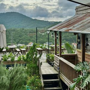 a patio with tables and chairs and a mountain at Cloudy Hillside Botique - Homestay in Ấp Ða Lợi