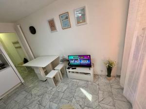 a living room with a white table and a tv at Charmant studio à 2 pas de la mer et du train in Roquebrune-Cap-Martin