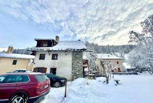 圣韦朗Casa-Le Gerland : joli duplex dans chalet St-Véran的雪覆盖的房子前的红色汽车