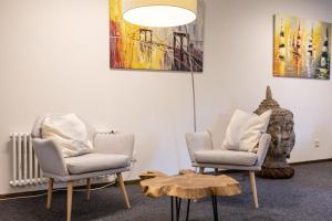 two chairs and a table in a room with paintings at Hotel Vetter in Nürtingen
