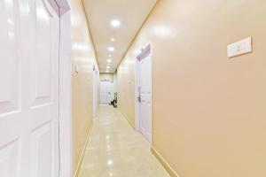 a hallway with white walls and a white door at Hotel O Poddar Inn in Dispur