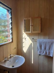 ein Badezimmer mit Waschbecken und Fenster und einem Handtuch in der Unterkunft Wilderness Views - Clermont Cottage in Wilderness