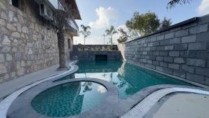 a swimming pool next to a stone wall and a building at Ekanta by nature in Pushkar