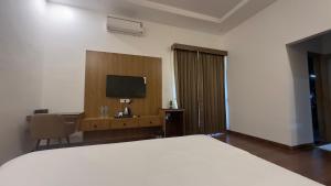 a bedroom with a bed and a desk with a television at Ekanta by nature in Pushkar