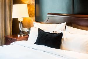 a bed with white pillows and a table with a lamp at Ostee Lodge in Ablajei