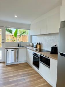a white kitchen with white cabinets and a window at Magpie Sands - Ocean Views & Seaside Luxury - Steps to beach in Aldinga Beach