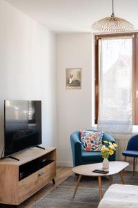 a living room with a blue couch and a tv at L'impasse - Maison avec jardin proche du centre in Rouen