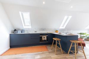 a kitchen with a blue counter and stools at Beautiful Self Contained Loft Studio Home in Rural Toddington in Toddington