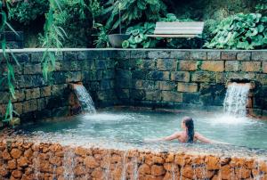 a woman in a swimming pool with a fountain at Coração das Furnas in Furnas