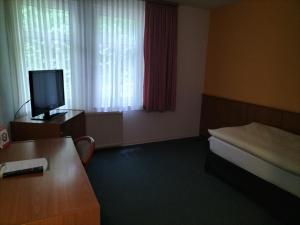 a small room with a bed and a television at Hotel und Restaurant am Bismarckturm in Erfurt