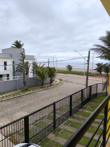 an empty street with a fence and palm trees at Pousada Beira Mar Peruíbe in Peruíbe