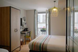 a bedroom with a bed and a desk and a window at Hotel Litteraire Marcel Ayme, BW Premier Collection in Paris