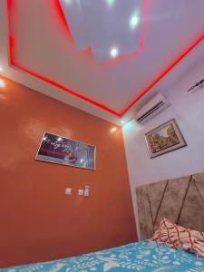 a bedroom with orange walls and a bed with a comforter at Bon séjour in Bouaké